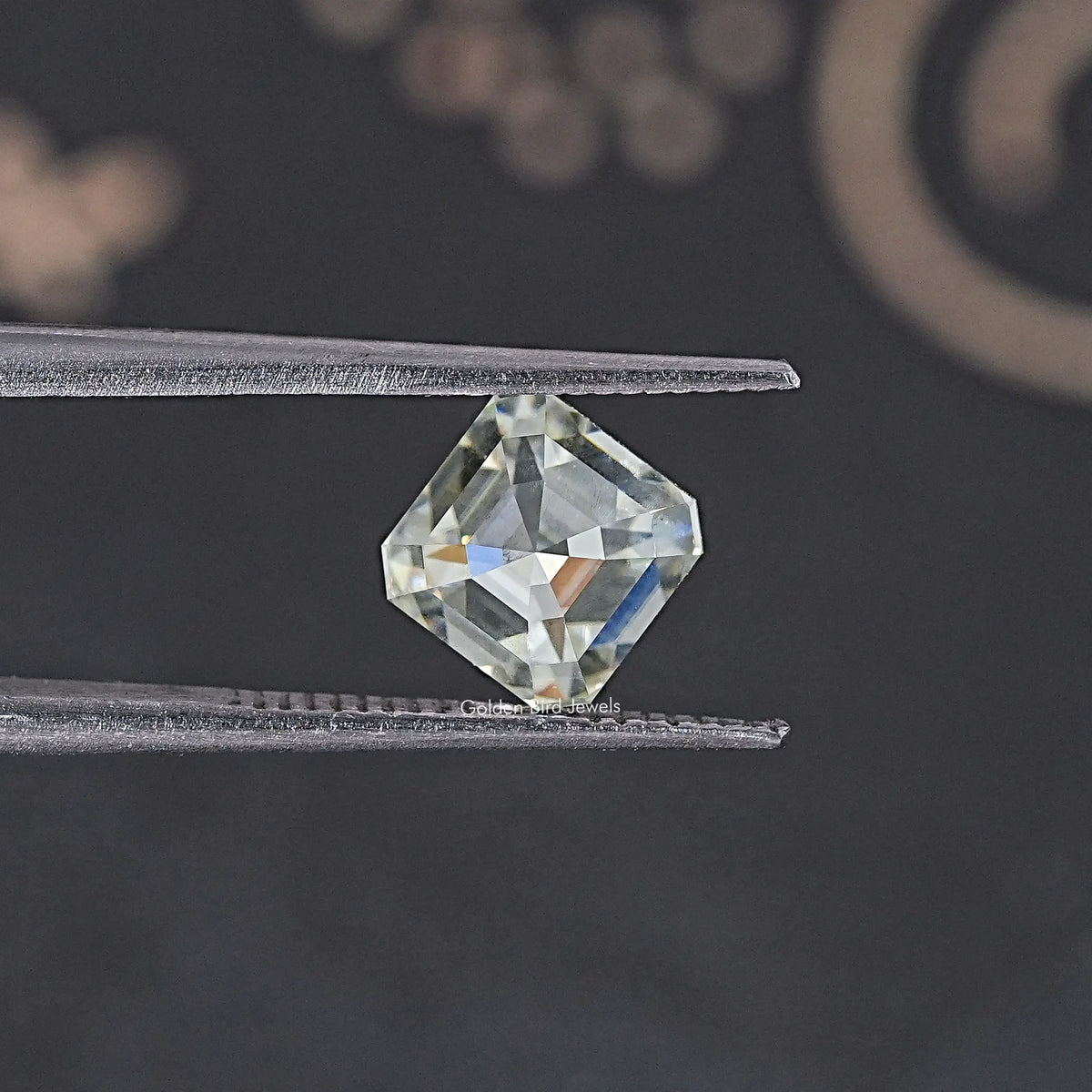 Asscher-cut moissanite loose stone held between tweezers, off-white, 2.85 CT