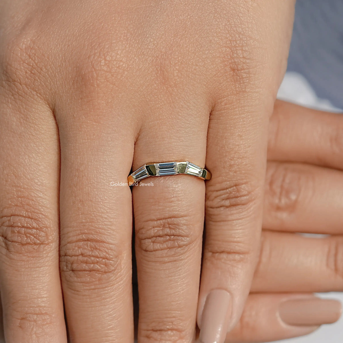 Three-stone baguette-cut ring on finger, close-up of rectangular center stone