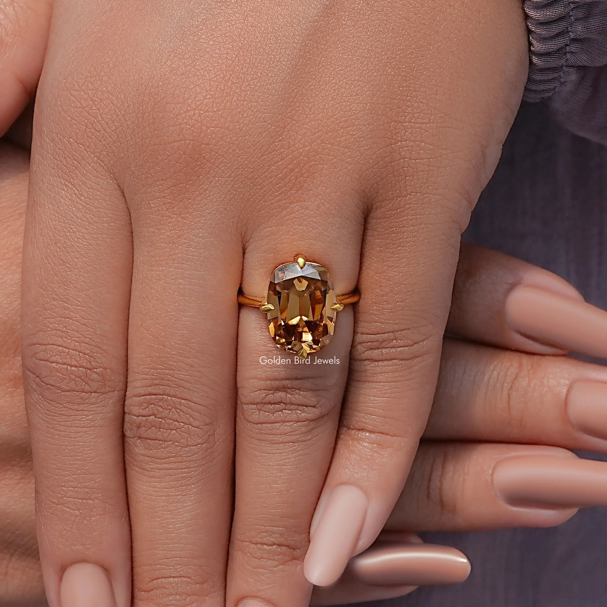 Solitaire cushion-cut moissanite ring on hand, golden center stone in gold prong setting
