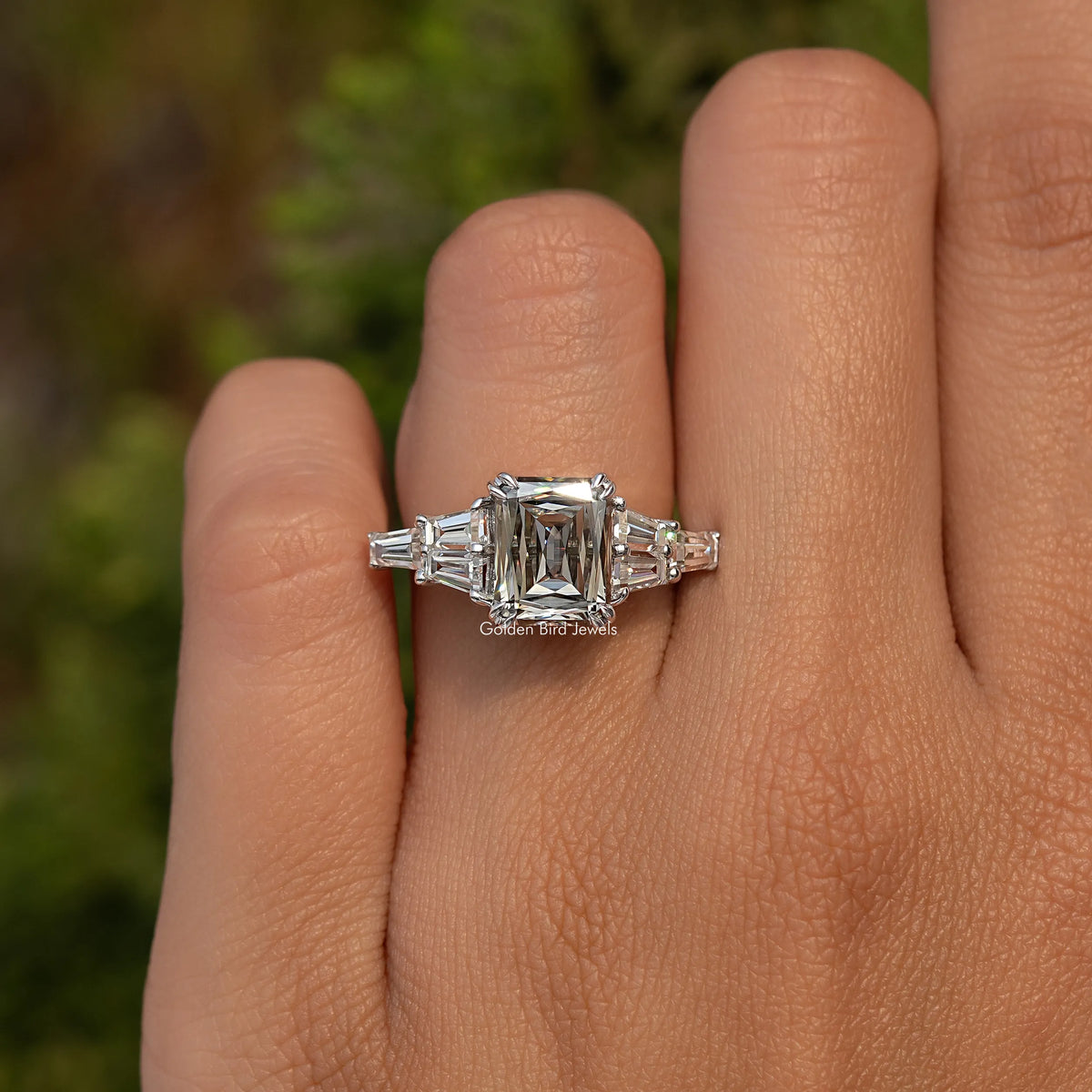 Sterling silver moissanite ring on hand with rectangular center stone and side baguette stones