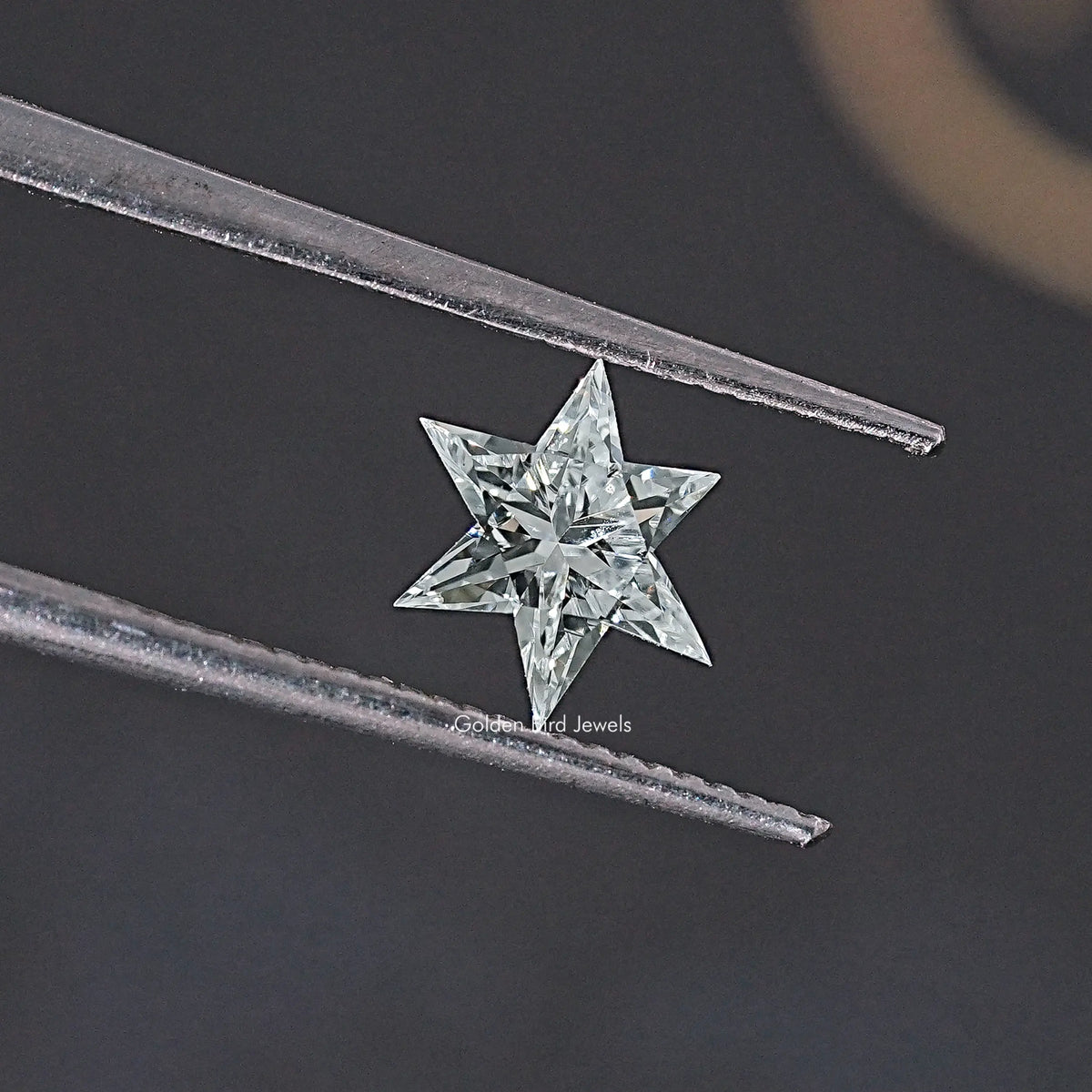 Star-cut loose lab-grown diamond held in tweezers, angled close-up
