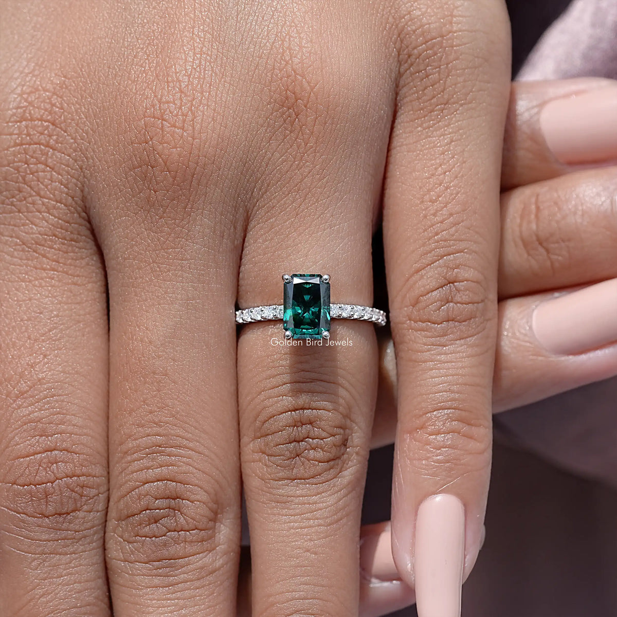 Close-up of sterling silver ring with green moissanite square center and side accents