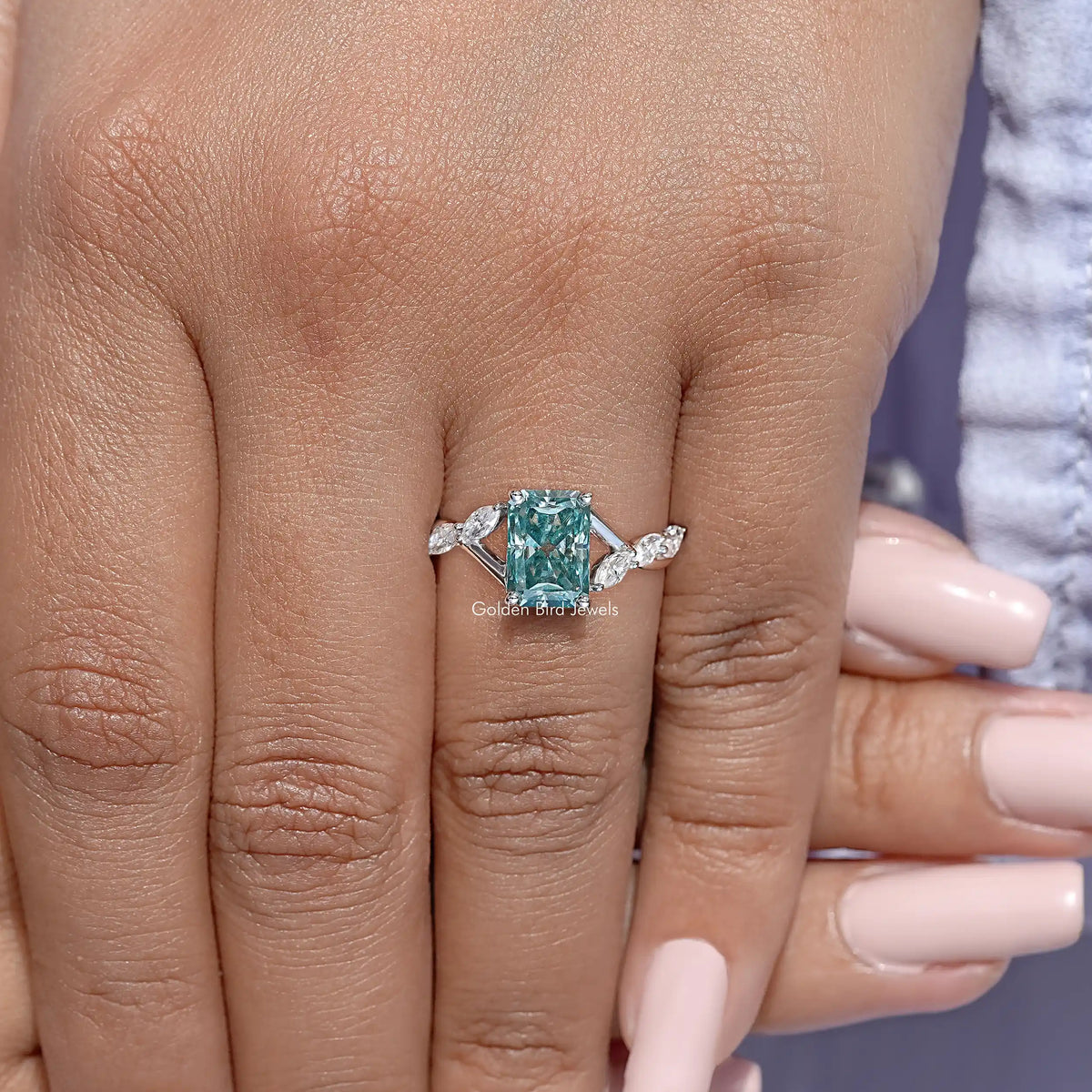Sterling silver ring on hand with teal emerald-cut center and sparkly side stones