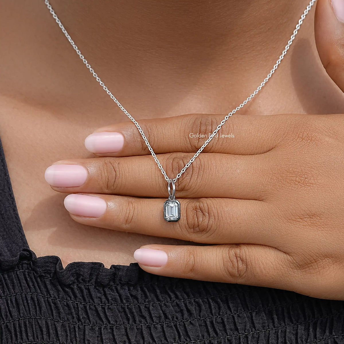 Rectangular bezel-set solitaire pendant necklace resting on hand
