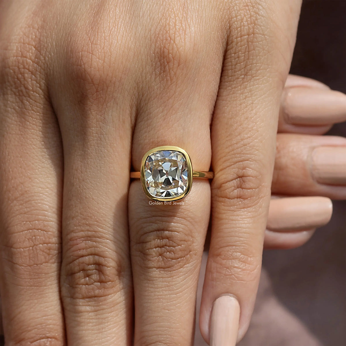 Cushion-cut moissanite bezel engagement ring, close view on hand and fingers