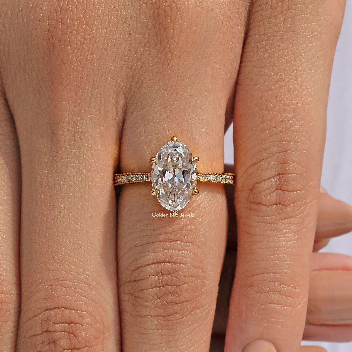 Oval-cut moissanite ring with pavé band, gold-tone setting