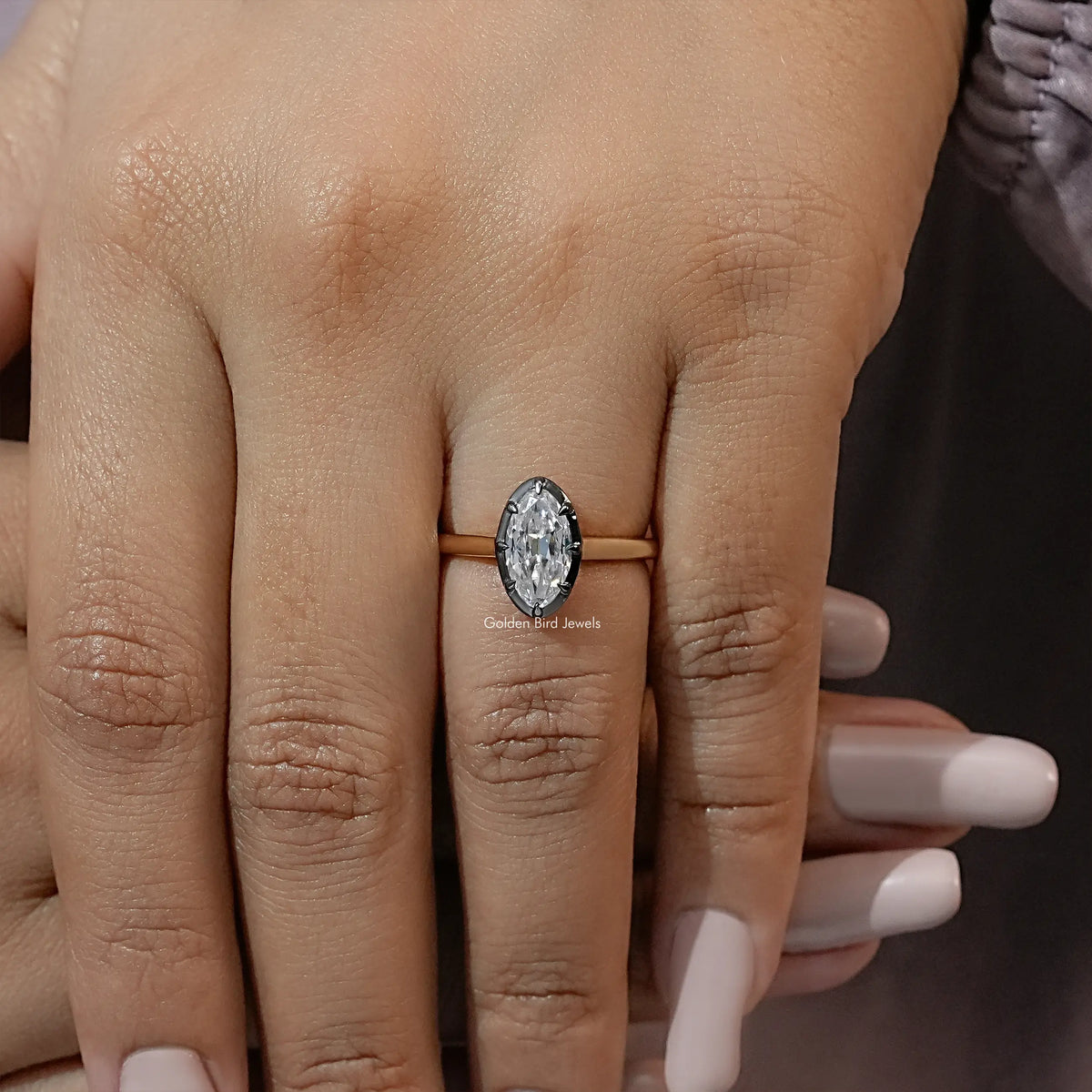 Oval moissanite solitaire ring with bezel setting on gold-tone band, worn on hand