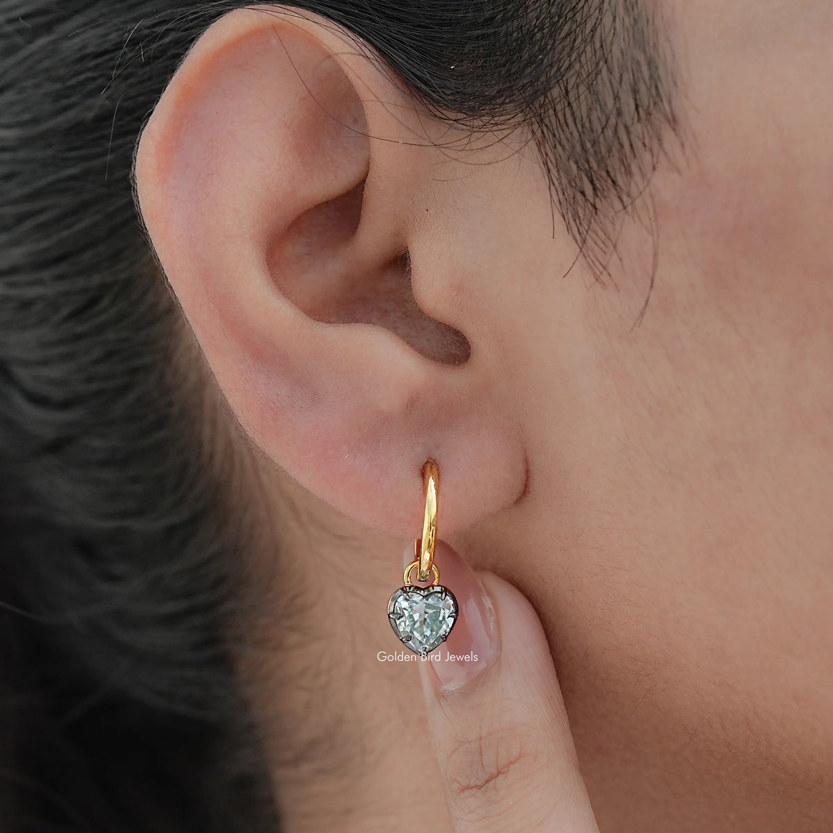Gold-tone dangle earrings with blue faceted gemstone drop, close-up