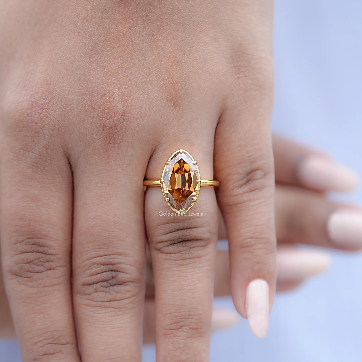 Gold-tone oval champagne solitaire ring on hand, side profile view