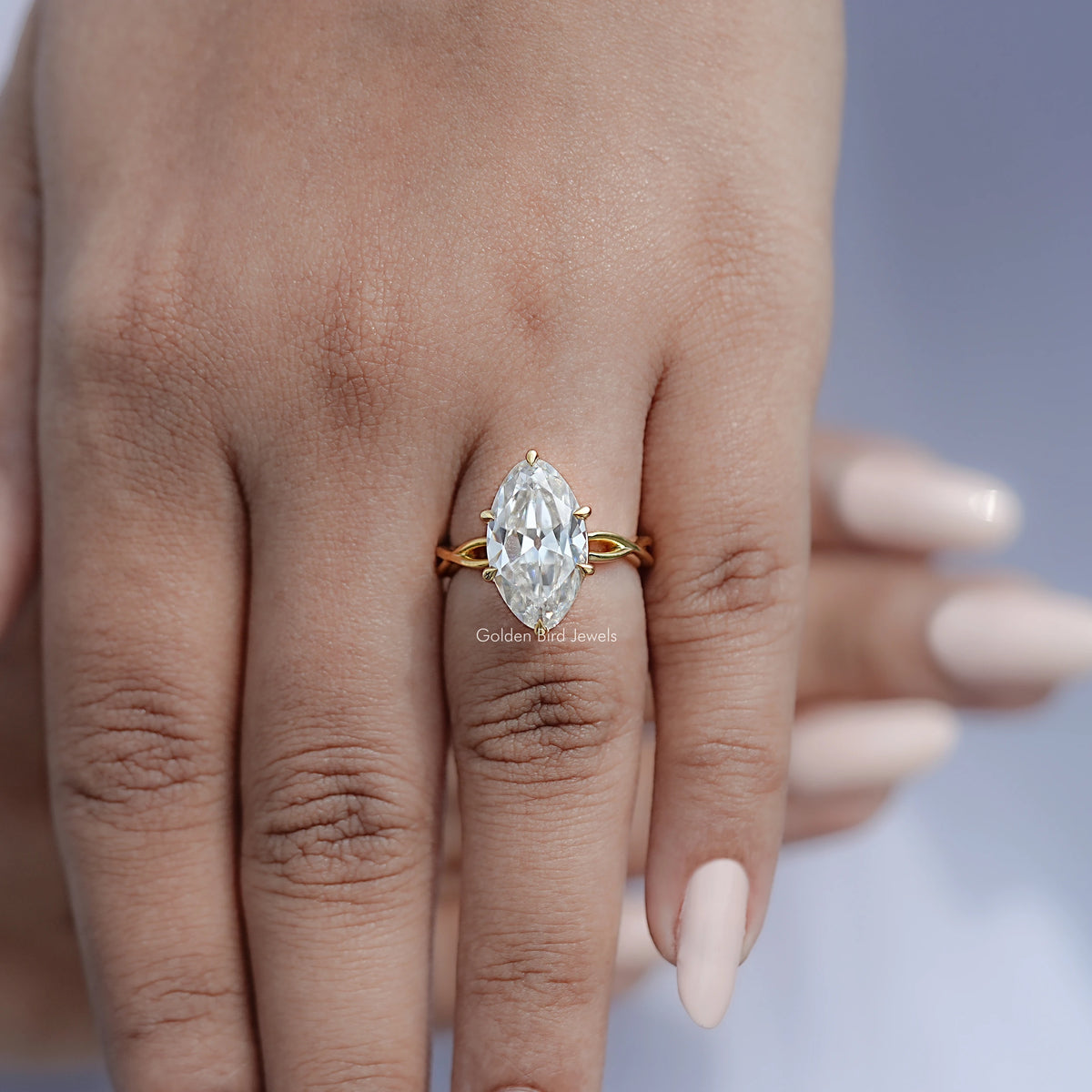 Gold-tone twisted shank solitaire ring with oval moissanite center stone