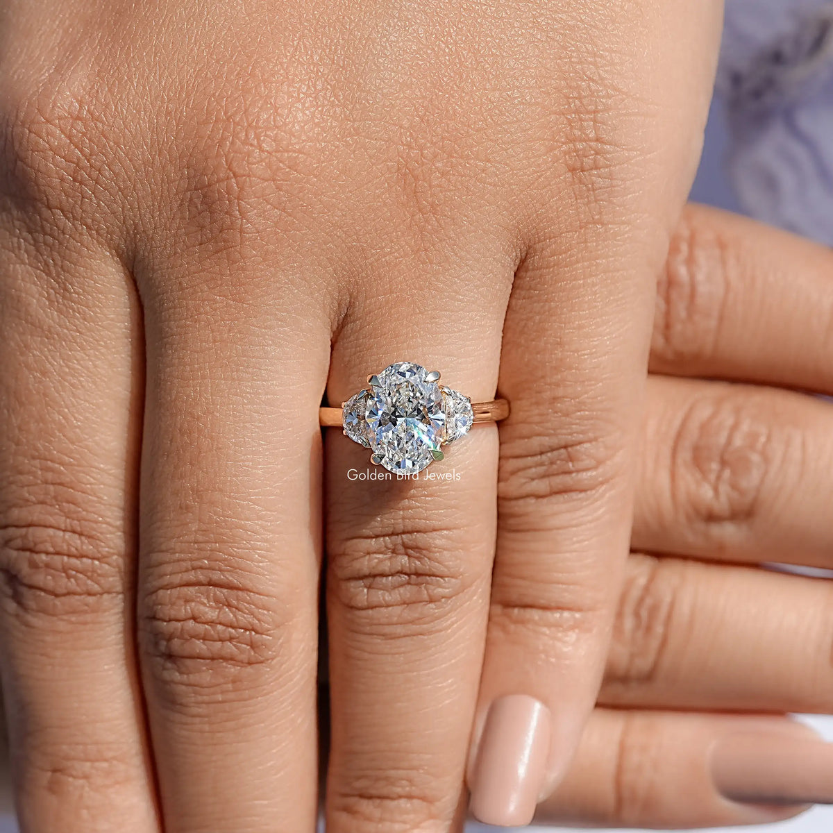 Three-stone diamond engagement ring with center stone and side stones, on fingers