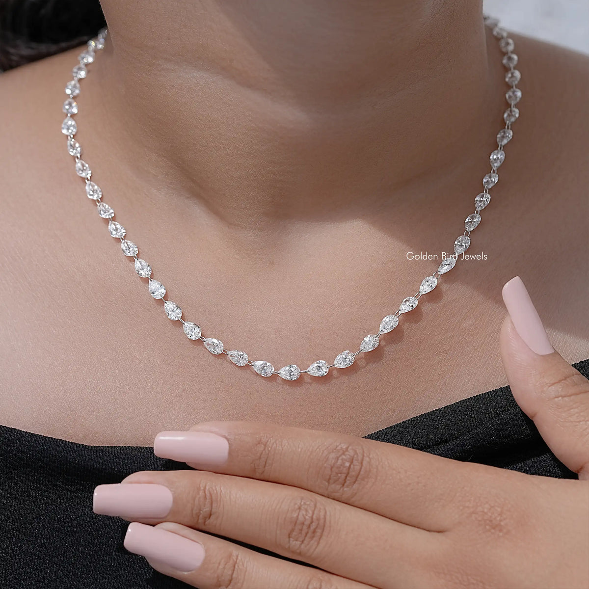 Silver pear-cut diamond tennis necklace with oval links, hand close-up