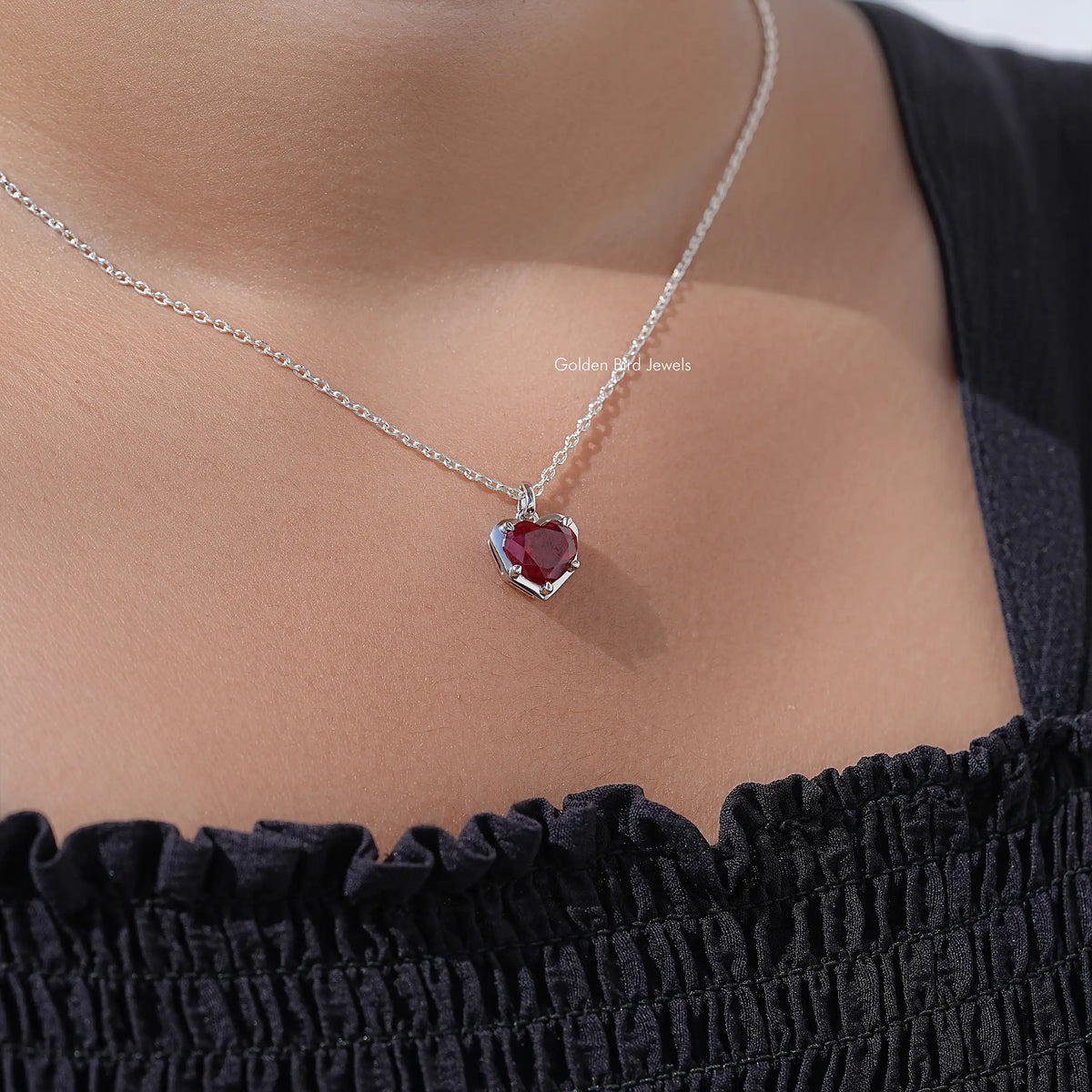 Silver chain heart solitaire necklace with red gem pendant at neckline