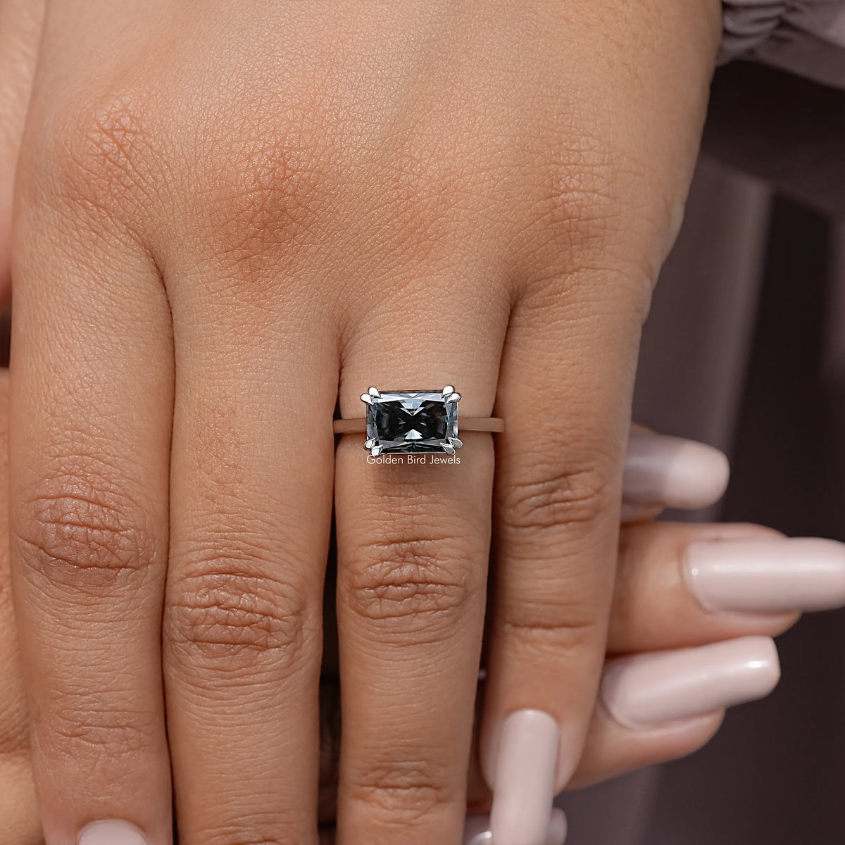 Silver solitaire engagement ring with black gemstone on open hand