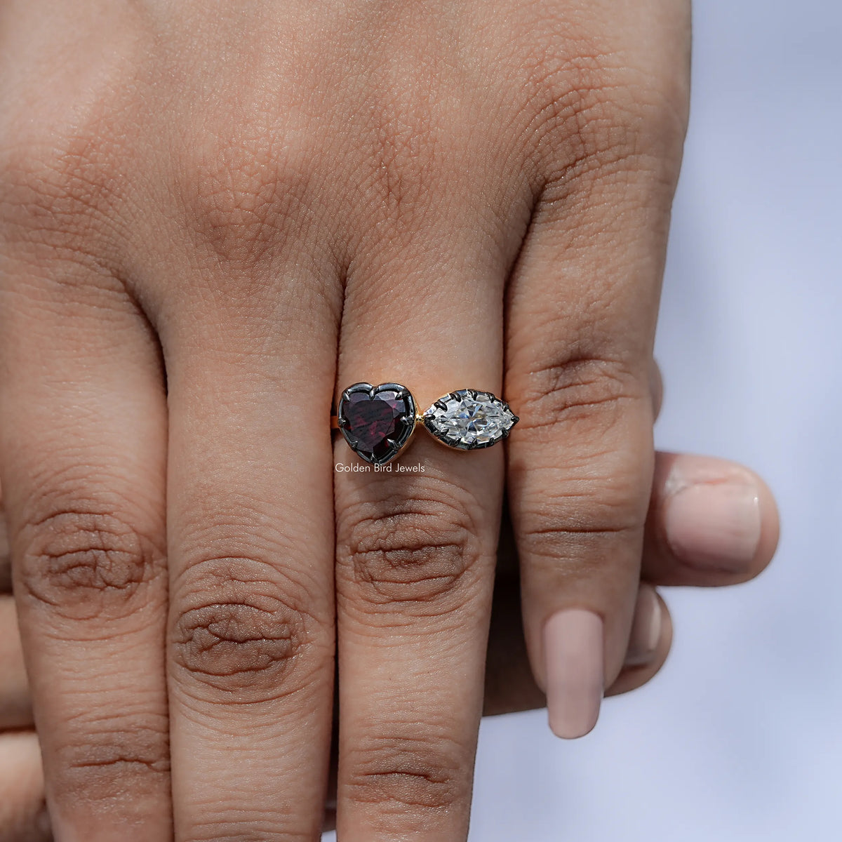 Heart two-stone ring on hand with dark heart gemstone and oval clear stone, silver-toned band