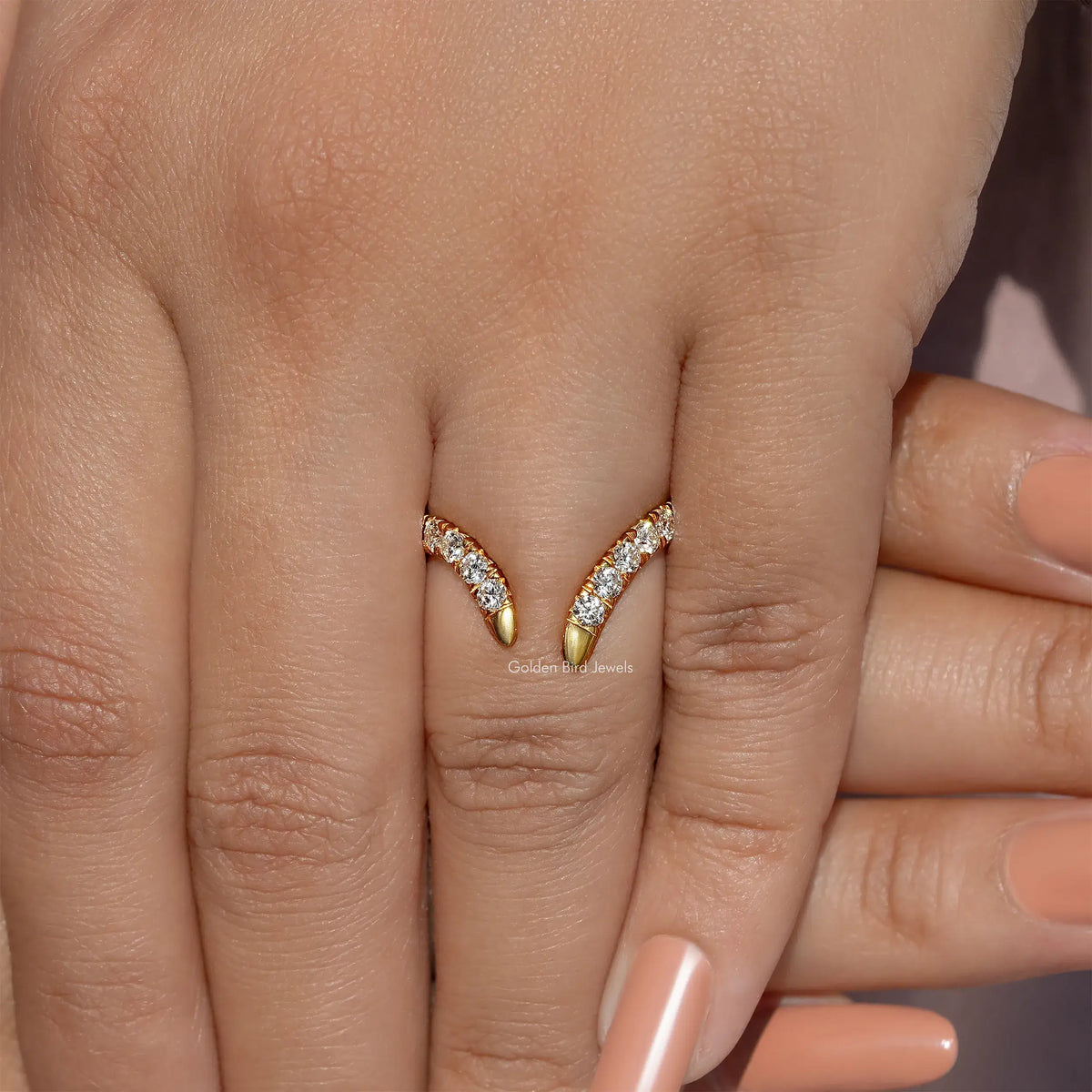 Gold open V-shape wedding band with round-cut stones, centered on fingers