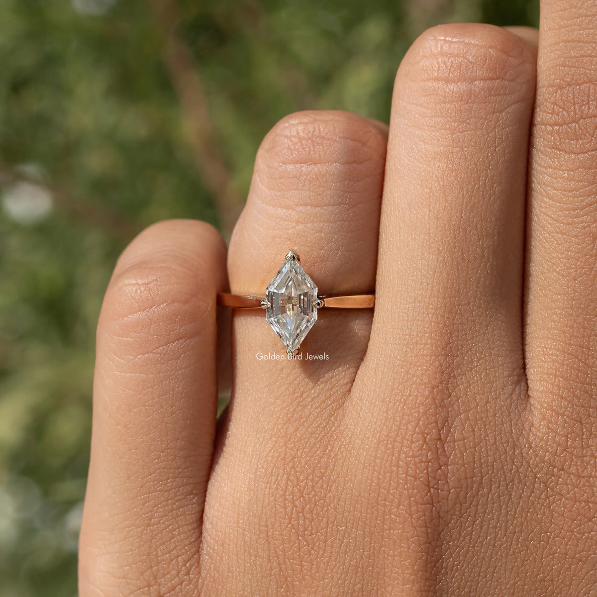 Gold-tone marquise step-cut moissanite ring on hand with slender band