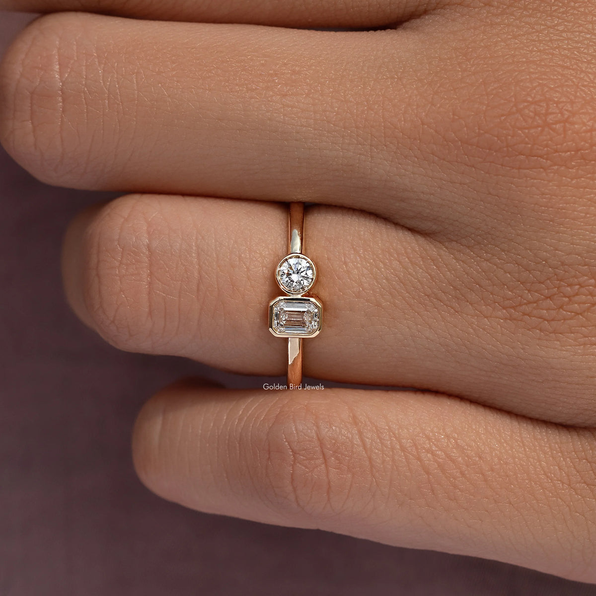 Gold-tone ring close-up with round and emerald-cut lab diamonds in an open bezel