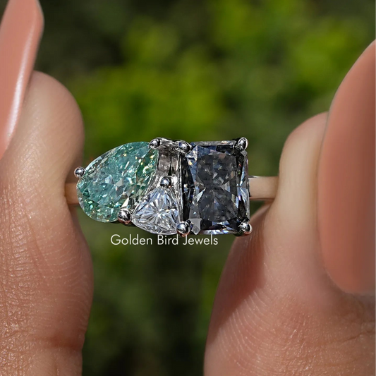 Three-stone moissanite engagement ring close-up, oval green center with two dark side stones