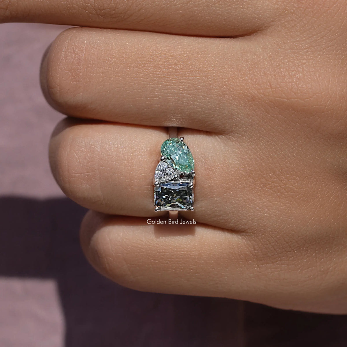 Three-stone moissanite ring detail, oval green stone with rectangular side stones