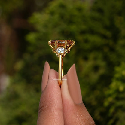 Three-stone ring with oval center stone and round side stones, prong setting