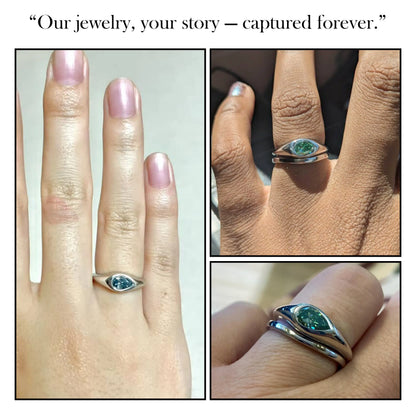 Green pear-cut solitaire ring on hand with slim metallic band