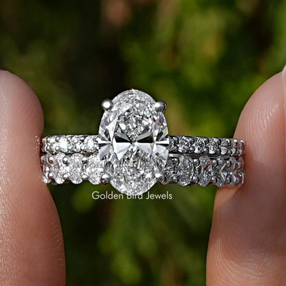 Oval Cut Lab Diamond Bridal Ring Set Held Between Fingers