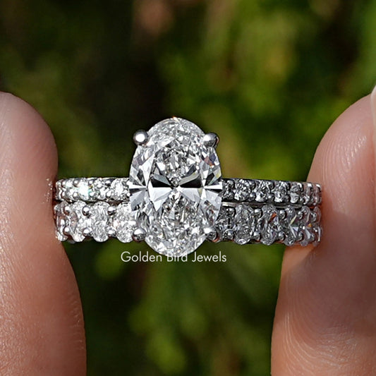 Oval Cut Lab Diamond Bridal Ring Set Held Between Fingers