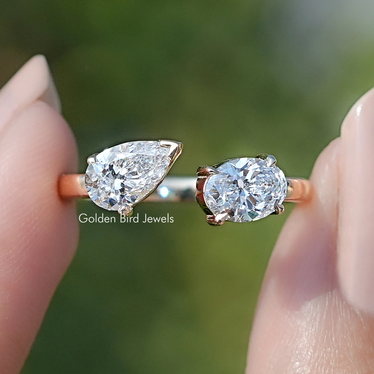 Front view of Open Cuff Pear And Oval Lab Diamond Two Stone Ring in two fingers 
