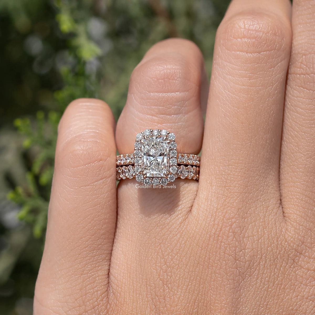 Radiant cut halo bridal ring set with pavé bands on a hand