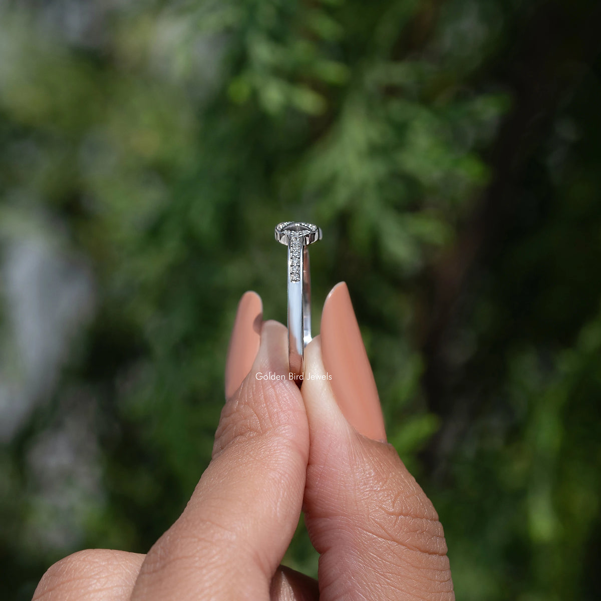 Moissanite ring top view with prong-set round-cut stones in a halo, silver tone