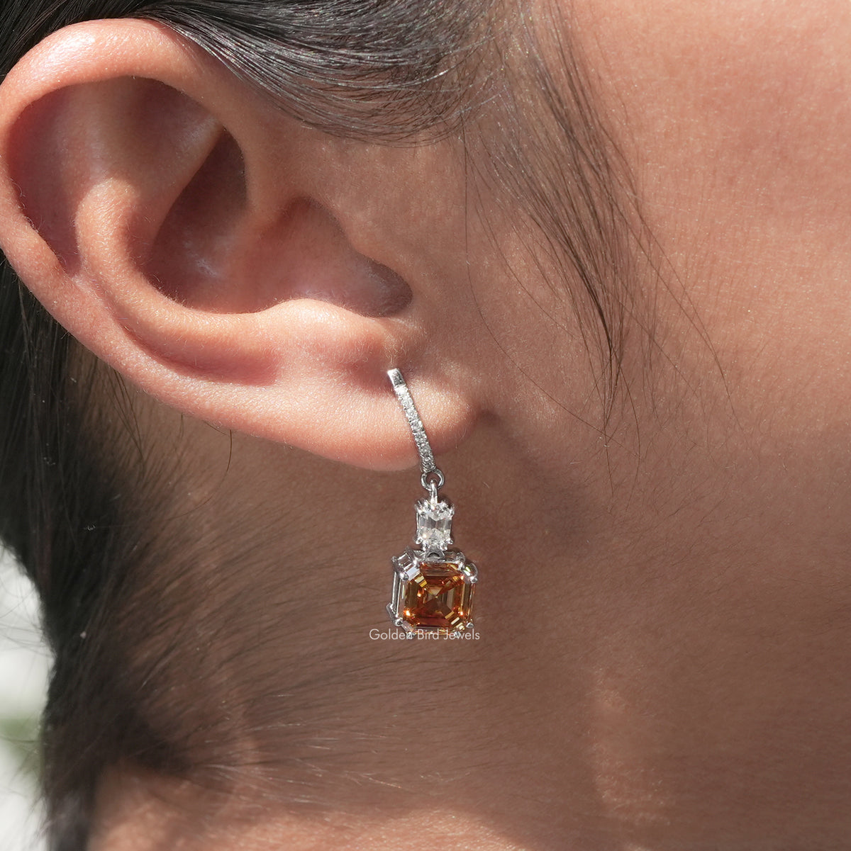 Silver drop earrings with a dangling Asscher-cut amber moissanite center stone