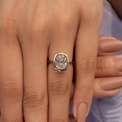 Gold-tone cushion-cut bezel set engagement ring with ornate band, close-up on hands