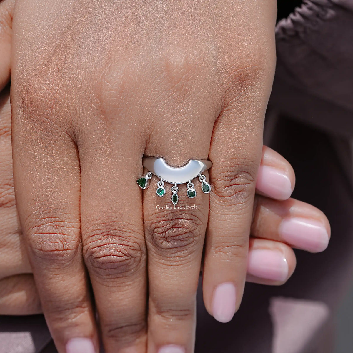 Curved engagement ring with green gemstones and scalloped bezel, silver band