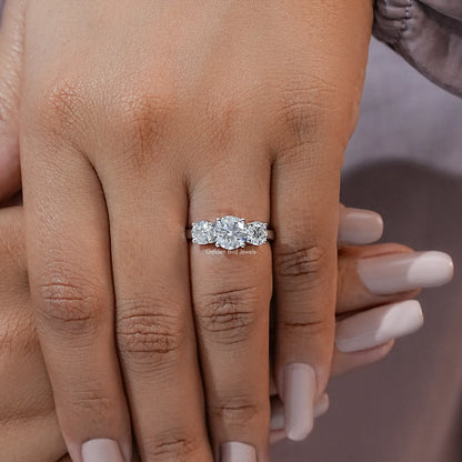 Three-stone moissanite ring on hand with round stones and slim silver shank