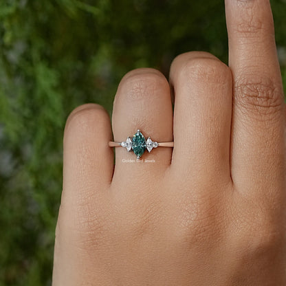 Three-stone engagement ring on finger, green marquise center flanked by two marquise stones