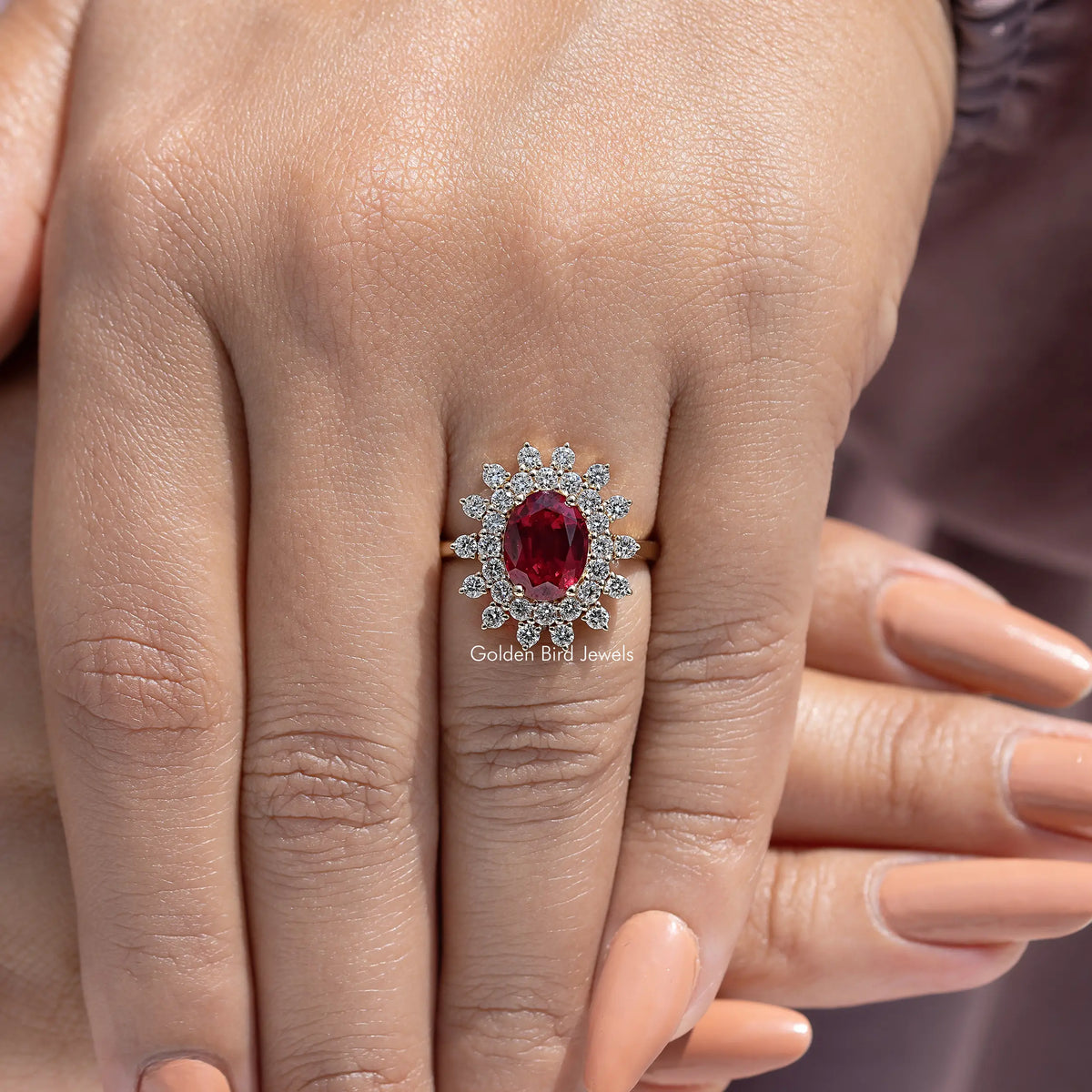 Red oval center gemstone with round halo accents on ring finger