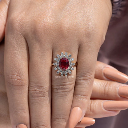 Red oval center gemstone with round halo accents on ring finger