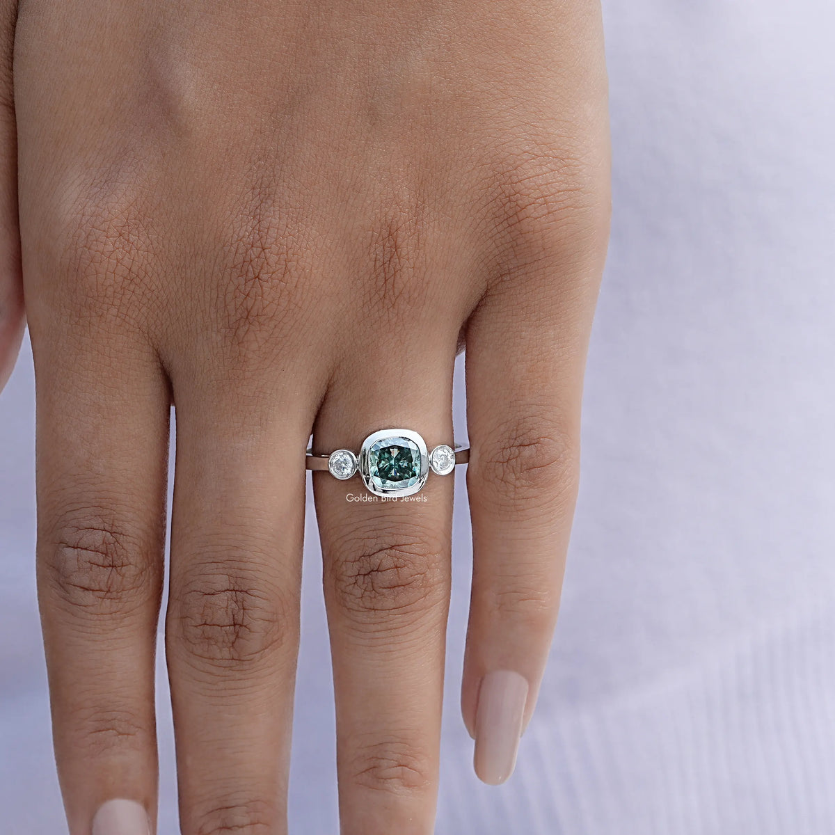 Three-stone cushion-cut moissanite ring on hand, silver band