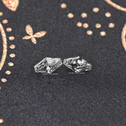 Modified lozenge-cut lab-grown diamond stud earrings, close-up of two clear faceted diamonds