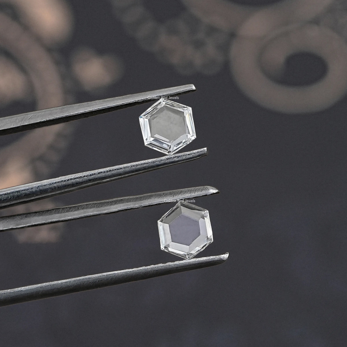 Two clear hexagon lab-grown loose diamonds held in tweezers, close angle