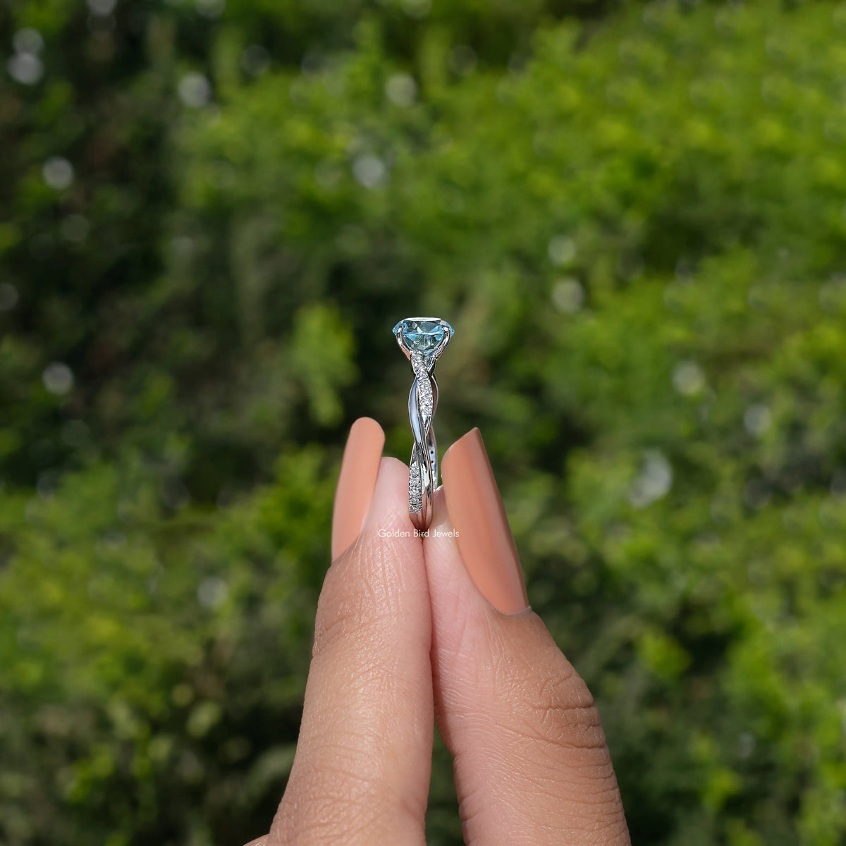 Aquamarine ring standing view with triangular halo prongs and round blue center stone