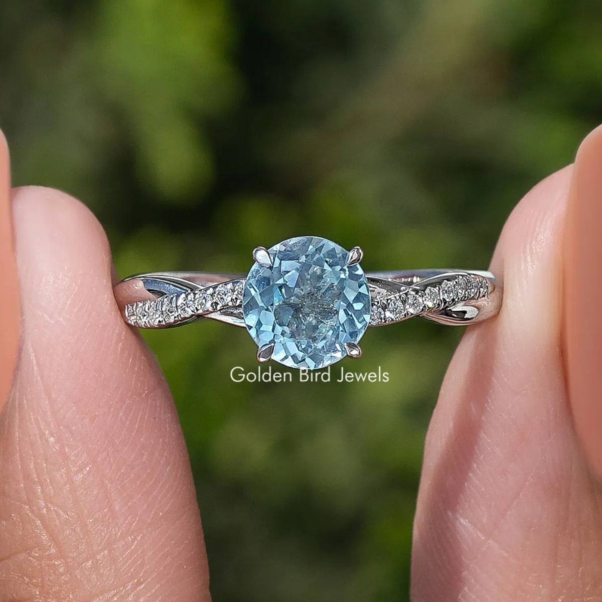 Aquamarine round-cut gemstone ring with prong-set blue center and pave side bands