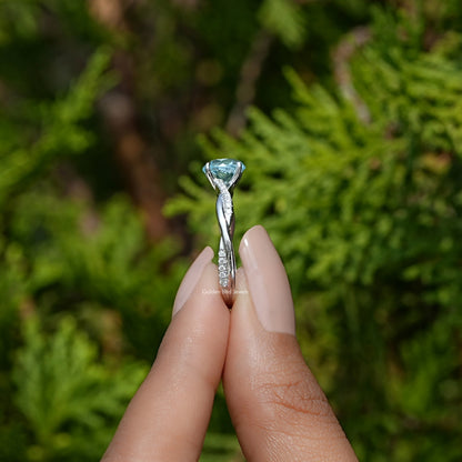 Side View of Round Cut Gemstone Engagement Ring In two fingers