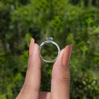 Silver gemstone ring viewed from side, showing open basket and top blue round stone