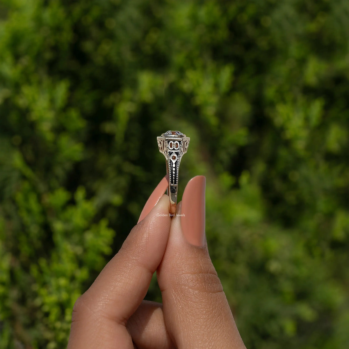 Vintage-style prong-set diamond engagement ring on finger, top view