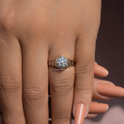 Diamond engagement ring on hand with ornate metalwork around the center stone