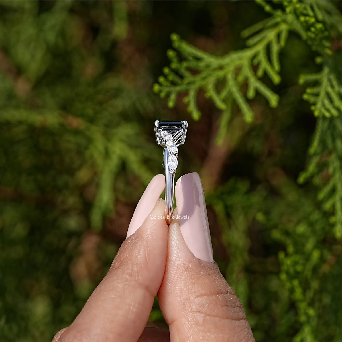 Black asscher-cut engagement ring viewed from the side, with prong-set sparkle stones