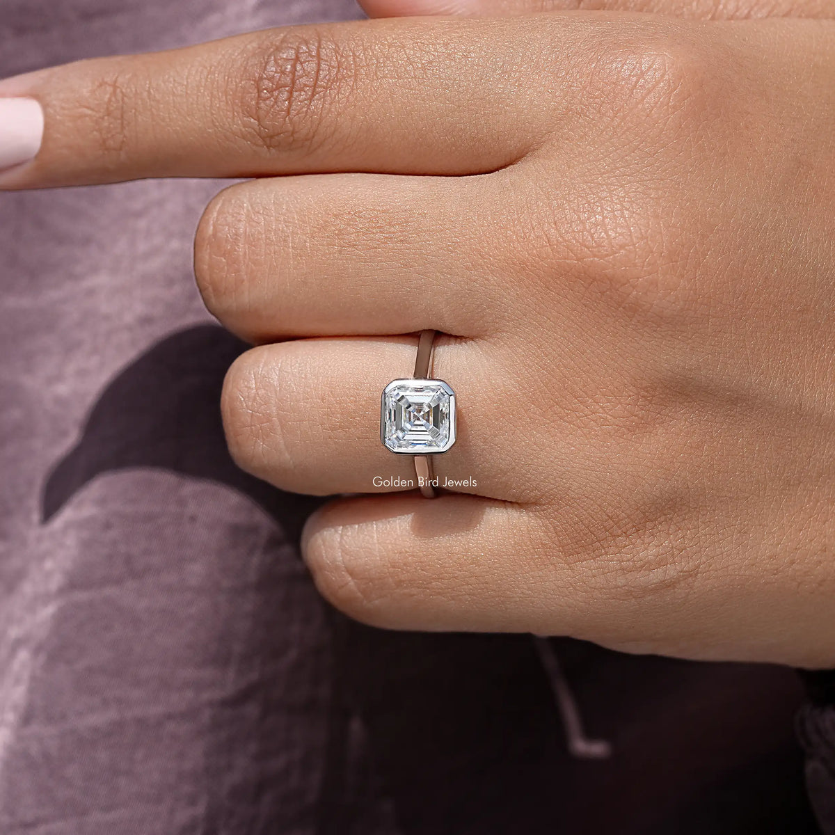 Sterling silver asscher-cut moissanite bezel-set engagement ring on finger, side angle