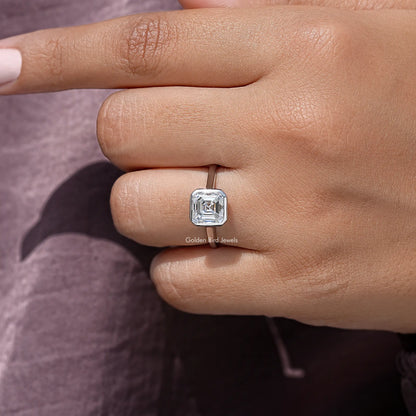 Sterling silver asscher-cut moissanite bezel-set engagement ring on finger, side angle